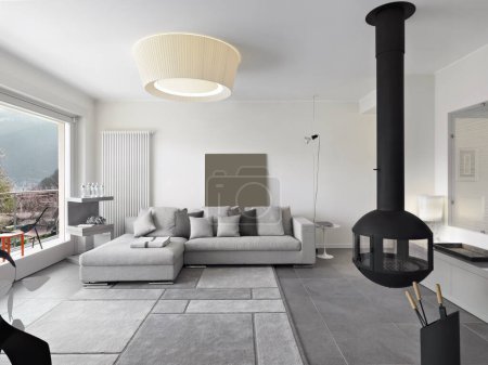 Téléchargez les photos : Modern living room interior with gray fabric sofa and carpet and an iron fireplace suspended from the ceiling - en image libre de droit