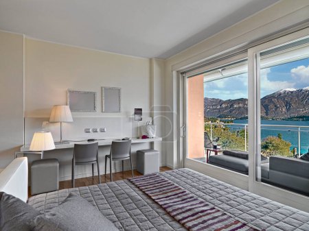Interior of a modern bedroom with a French window overlooking the lake of Como