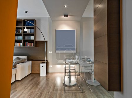 Foto de Interior de un moderno comedor frente a hay una mesa y sus sillas, a la izquierda hay un sofá y una estantería, mientras que el piso está hecho de madera - Imagen libre de derechos
