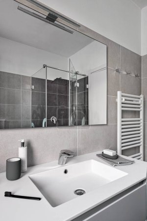 Téléchargez les photos : Plan intérieur d'une salle de bain moderne au premier plan le lavabo intégré sur le fond le radiateur, réfléchi par le miroir, vous pouvez voir la cabine de douche en verre - en image libre de droit