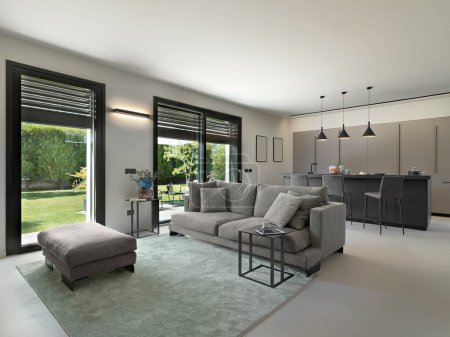 Foto de Interior de la moderna sala de estar en primer plano el sofá de tela con el taburete y la alfombra en el fondo la cocina se puede vislumbrar - Imagen libre de derechos