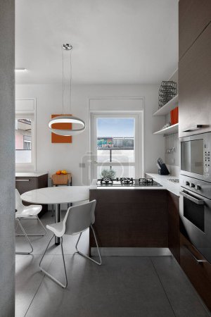 Foto de Vista interior de una cocina moderna en primer plano la mesa de comedor con sus sillas en el techo la lámpara colgante moderna - Imagen libre de derechos