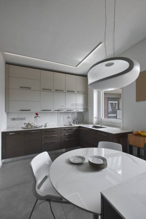 Foto de Vista interna de una cocina moderna en el primer plano de la mesa de comedor con la lámpara de araña de diseño - Imagen libre de derechos