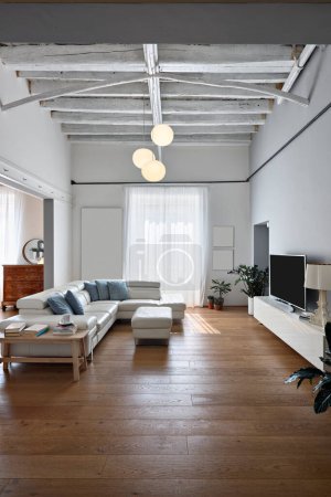 Foto de Vista interior de una sala de estar moderna, el sofá está frente a un gabinete de televisión, el piso y el techo están hechos de madera, en el fondo la ventana - Imagen libre de derechos