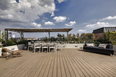 Foto de Fotografía exterior de una terraza con vistas a los tejados de Milán con un suelo de madera, una mesa de comedor y un sofá de tela - Imagen libre de derechos
