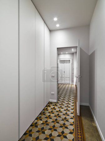 Téléchargez les photos : Gros plan d'un couloir avec carrelage antique dont les murs sont équipés de rangements blancs - en image libre de droit