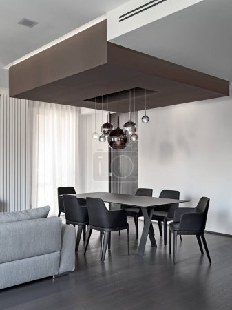 Téléchargez les photos : Gros plan de la table à manger et des chaises en cuir dans une salle à manger moderne, dont le sol est fait d'un bois foncé - en image libre de droit