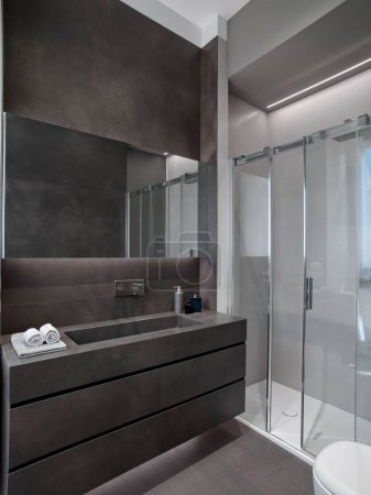 Foto de Primer plano de un gabinete del lavabo del cuarto de baño a la derecha está la caja de ducha de cristal el piso está hecho de madera - Imagen libre de derechos