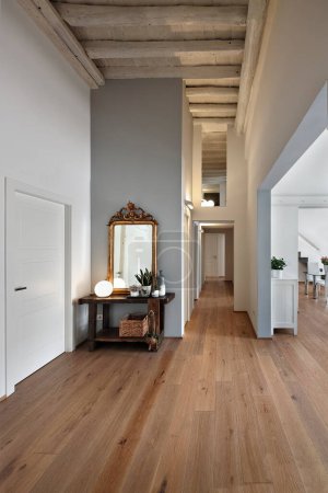 Foto de Vista interior de una entrada de un apartamento moderno con suelo de madera, en primer plano hay un banco de carpintero viejo y el espejo de oro - Imagen libre de derechos