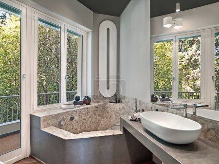 Téléchargez les photos : Vue intérieure d'une salle de bain moderne au premier plan le lavabo sur le dessus de la maçonnerie et dans le coin sur le fond sous la fenêtre il y a la baignoire en maçonnerie - en image libre de droit