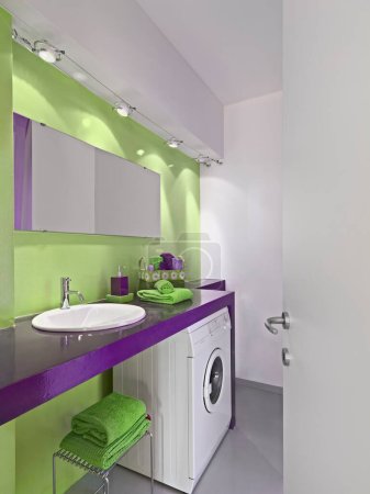 Foto de Vista interior de un moderno baño con suelo de resina y la lavadora la pared es de color verde - Imagen libre de derechos