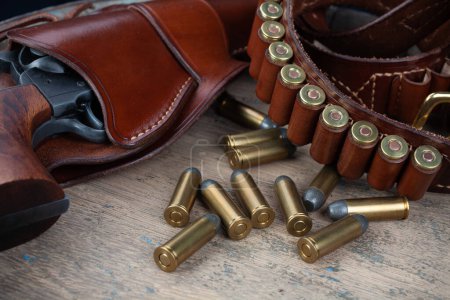 Pistola Wild West con cinturón, funda y munición sobre mesa de madera