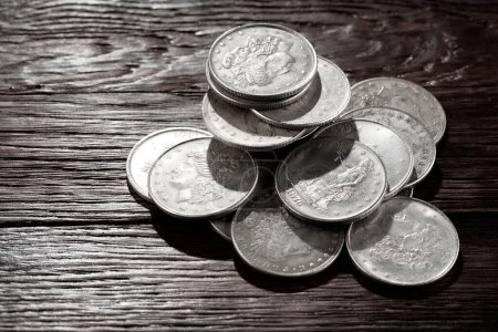 Stack of US old west dollar silver coins on wooden deck.