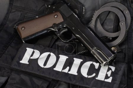 Police handgun with handcuffs on black uniform background