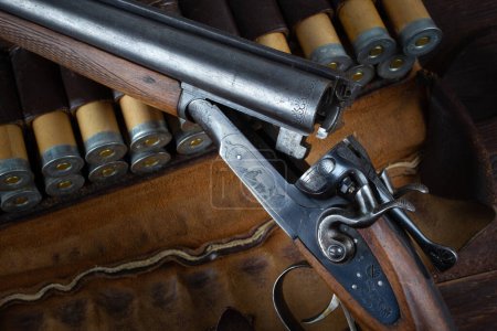 Antiquité fusil de chasse à action de rupture de calibre 12 avec étui en papier sur table en bois.