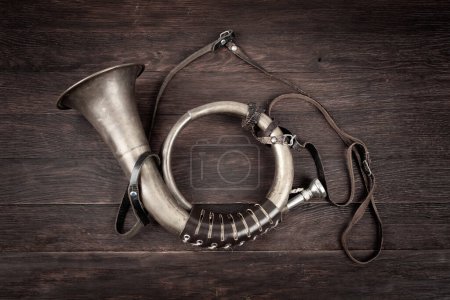 Hunting horn on rustic wood plank background.
