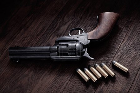 Old west 45 caliber peacemaker revolver with cartridges on wooden table