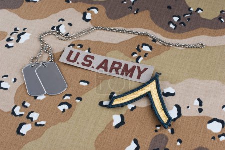US ARMY private t rank patch and dog tags on Desert Battle Dress Uniform background