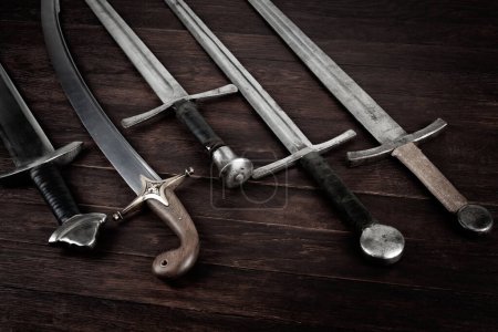 Épées vintage et sabre sur fond en bois.
