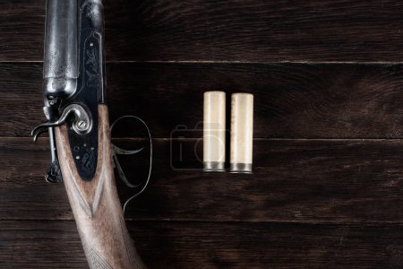 Fusil de chasse lisse à action de rupture de calibre 12 avec cartouches de papier sur table en bois.