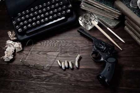 Antique typewriter and revolver gun with ammunitions, books, blank paper, old ink pen pen on wooden table