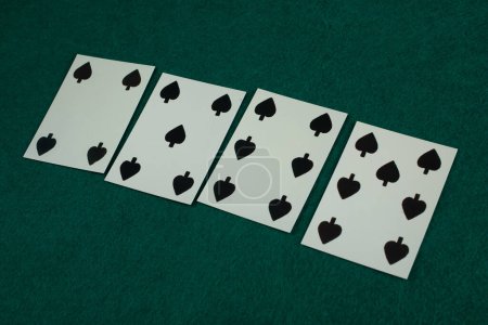 Old west era playing card on green gambling table. 4, 5, 6, 7 of spades.