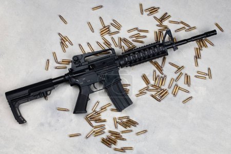 M4 carbine and 5.56mm shells and magazine with bullets on grey concrete surface background