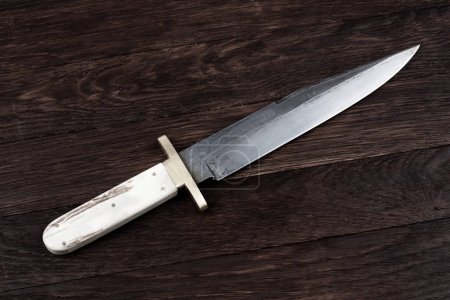 Old west bowie knife on wooden deck background