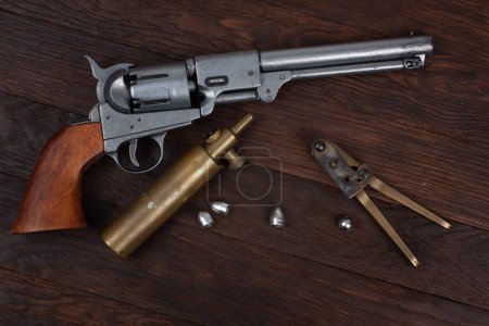 Old West Revolver with bullet mold and bullets on wooden background.