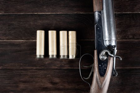 fusil de chasse latéral à double canon avec cartouches de papier sur table en bois.
