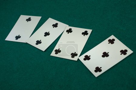 Old west era playing card on green gambling table. 2, 3, 4, 5 of clubs.