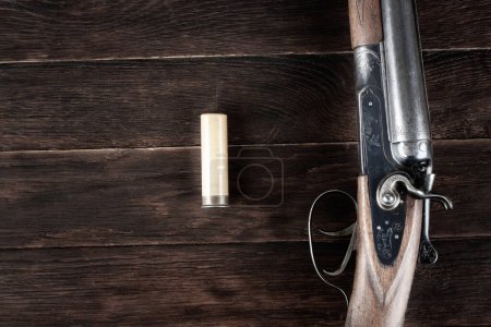 fusil de chasse latéral à double canon avec cartouche de papier sur table en bois.