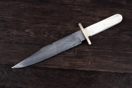 Old west bowie knife on wooden deck background