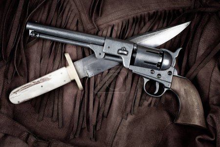 Old West Revolver with bowie knife on leather jacket background