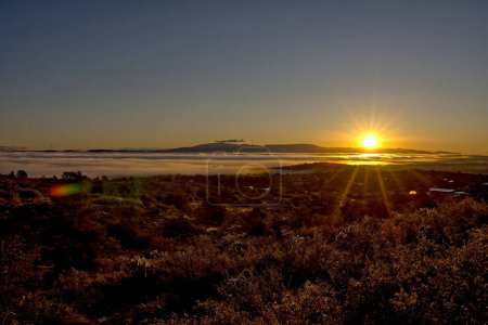 Morning sun rising over Mingus Mountain near Chino Valley Arizona illuminating fog rolling across the landscape.
