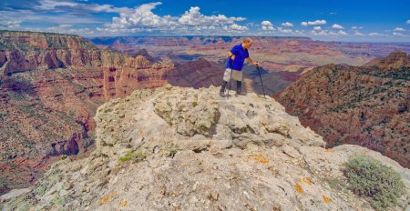 A hiker on the edge of a cliff along Buggeln Hill Trail halfway between Grandview Point and the Sinking Ship at Grand Canyon Arizona.