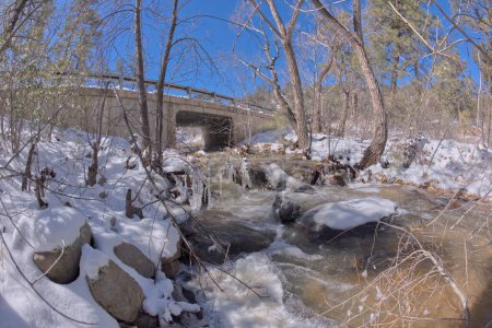 Miller Creek flowing under a bridge at the Thumb Butte Recreation Area in the Prescott National Forest just west of Prescott Arizona, covered in winter snow and ice.