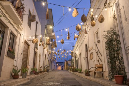 Photo for Alberobello, Italy with hanging hatwear in an alleyway at twilight. - Royalty Free Image