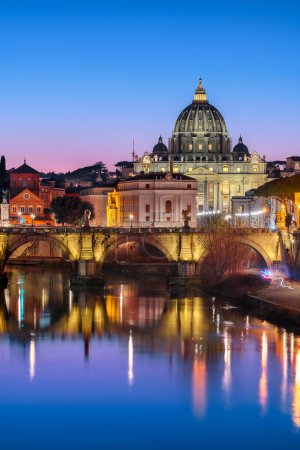 St. Peter's Basilica in Vatican City with the Tiber River passing through Rome, Italy at dusk.