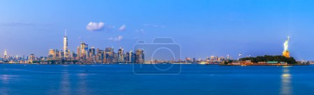 Photo for New York, New York, USA skyline from the harbor with Ellis Island and the Statue of Liberty at dusk. - Royalty Free Image