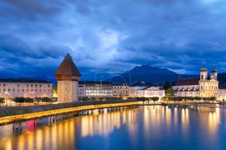Photo for Lucerne, Switzerland with the Chapel Bridge over the River Reuss with Mt. Pilatus in the distance at dusk. - Royalty Free Image
