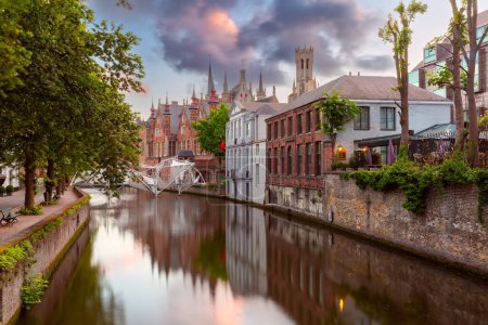 Scenic evening cityscape with medieval tower Belfort and Green canal at sunset, Bruges, Belgium