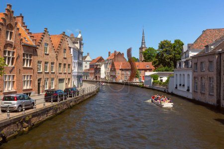 Tourists on a boat tour explore the medieval city, canal with Dutch houses, Bruges, Belgium