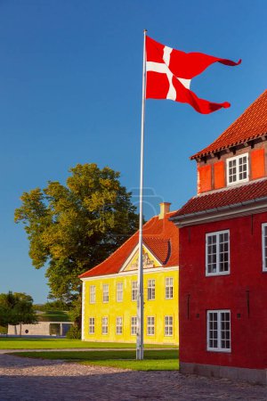 Bandera danesa ondea sobre Royal Barracks al atardecer en Copenhague, Dinamarca, Kronprinsessegade Park