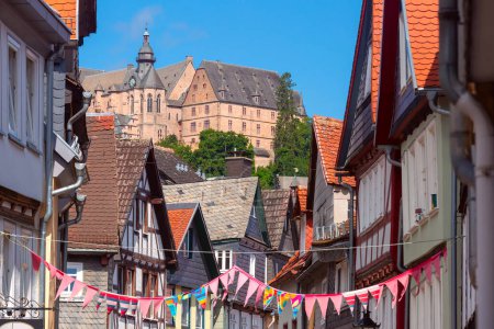 Casas tradicionales enmarcadas en madera bordean la calle empedrada que conduce al Castillo de Marburgo, Alemania