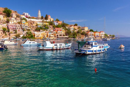 Hillside view of the colorful buildings and busy harbor on Symi Island, Greece.