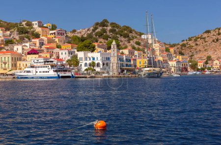 Sonniger Blick auf Ano Symi mit bunten Häusern und Uhrturm, Dodekanes Inseln, Griechenland