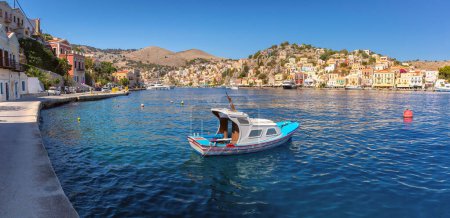 Panoramic harbor view with traditional fishing boat on Symi Island, Greece