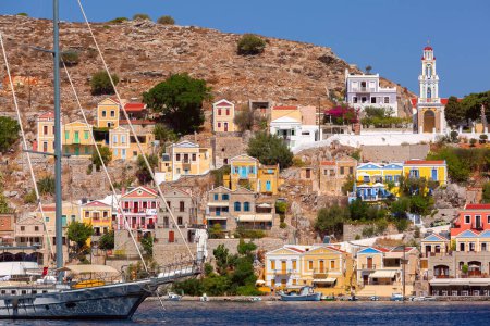 Sonniger Blick auf Ano Symi mit bunten Häusern und Verkündigungskirche, Dodekanes, Griechenland