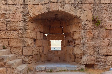 Ruines historiques en arc de pierre à Rhodes avec bateau visible par la fenêtre, Grèce